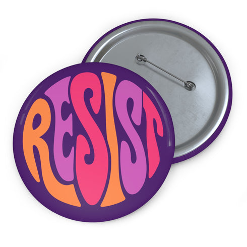 Close-up of a glossy, round purple pinback button. The button features the word "RESIST" in a bold, 70s-style psychedelic font that fills the entire surface. The bubbly, wavy letters alternate in color between a vibrant orange, a light peach-pink, and a deep magenta, creating a powerful and retro statement piece. The design has a distinct groovy and feminist protest aesthetic, making it a perfect accessory for jackets, bags, or activist apparel.