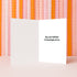 a white card with a holiday message on it, placed against a background of orange and pink ribbons.