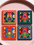 A set of four square coasters featuring a glossy glazed finish and vibrant insect illustrations. Each coaster measures approximately four by four inches. The designs showcase symmetrical beetles and spiders in bold red, blue, and orange colors, framed by intricate floral and geometric borders in a maximalist folk art style. Available in ceramic with cork backing or hardboard MDF. The edges are smooth. The designs are vivid and highly saturated, designed to provide grip and protect furniture.