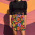 Honey Dazed retro floral mini skirt in a fitted pencil silhouette with high waist. Features a groovy all-over print of oversized flowers, checkers, waves, and bold 70s-inspired shapes in orange, red, purple, green, and yellow. Designed with a soft, sculpting stretch fabric for all-day comfort and drama. A statement piece made for maximalists, festival-goers, and vintage fashion freaks. Perfect for layering with puff sleeves and platform boots.