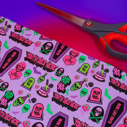 Vibrant purple wrapping paper with gothic-inspired design for 50th birthdays. Features colorful skulls wearing party hats, coffins, 'RIP 40s' tombstones, and 'Youth Dies Here' text. Perfect for edgy, humorous gifts to 50-year-olds.