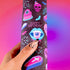 Spooky birthday wrapping paper with neon pink skulls, blue coffins, eyeballs, and bats on black background. Vibrant and gothic design for unique gift presentation.
