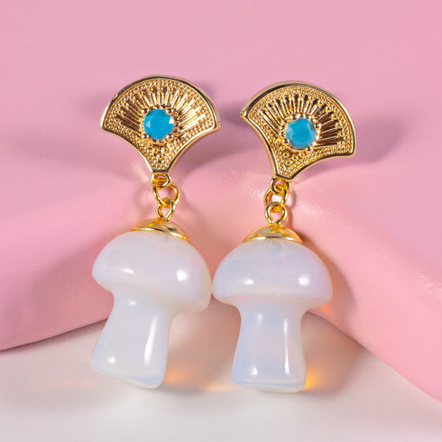 Exquisite earrings featuring ornate golden fan-shaped studs with azure stones, suspending lustrous opal mushroom charms, embodying luxurious cottagecore aesthetics.