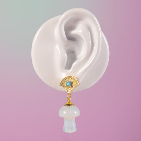 Exquisite earrings featuring ornate golden fan-shaped studs with azure stones, suspending lustrous opal mushroom charms, embodying luxurious cottagecore aesthetics.