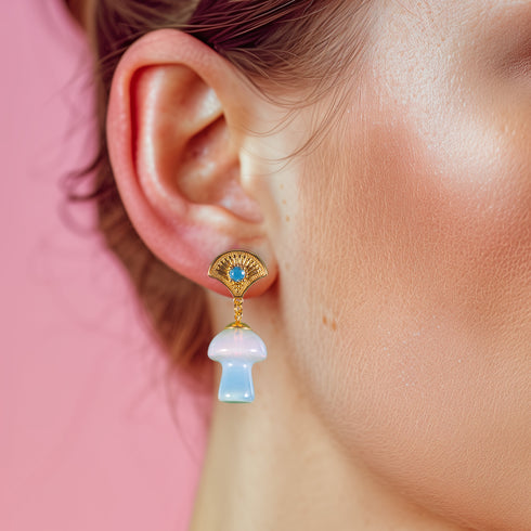 Exquisite earrings featuring ornate golden fan-shaped studs with azure stones, suspending lustrous opal mushroom charms, embodying luxurious cottagecore aesthetics.
