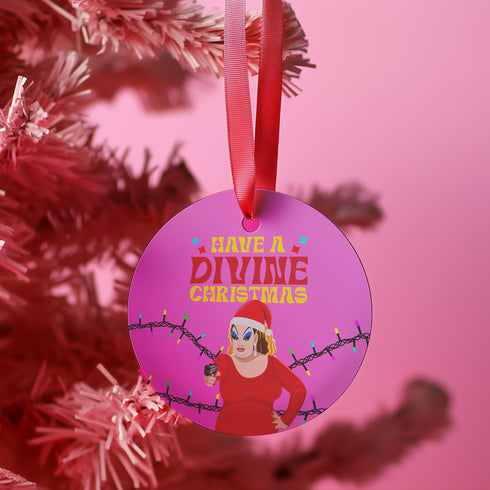 Round purple metal Christmas ornament featuring Drag Queen Divine in Santa hat and red dress with colored Christmas lights. Text reads "Have A Divine Christmas" in retro psychedelic lettering.