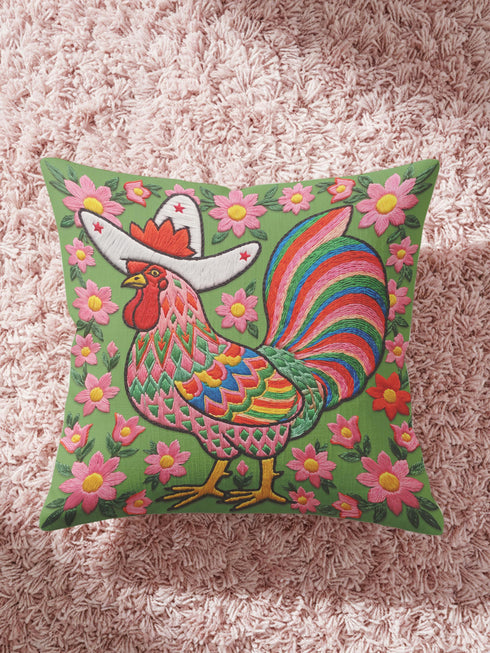 Square throw pillow cover with a printed faux embroidery design of a rooster wearing a white cowboy hat with red stars on a grass green background. The western chicken has a red comb and wattle, yellow beak and feet, and layered feathers in pink, green, orange, blue, and yellow with a rainbow striped tail. Pink and red flowers with yellow centers frame the bird. The stitched look is a flat 2D print on a smooth linen feel polyester cover with a hidden zipper, not raised embroidery.