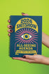 A hardcover spiral planner for 2026 with a dark blue cover and retro 70s style graphics. The title reads "2026 SHITSHOW All-Seeing Agenda" in bold yellow and pink text. Below the title is a large, stylized all-seeing eye with pink rays emanating from it. At the bottom, a pink ribbon contains the text "BLINK TWICE FOR MERCY." The back cover is also dark blue with a yellow sun graphic and the text "Plans bloom. Deadlines hum. I write, I wander, then get it done. Keep receipts. Keep grace.