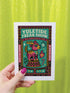 Maximalist Yuletide Freak Show 5x7 folded greeting card with a pearlescent shimmer finish. Features a vibrant, retro circus illustration in teal, pink, and yellow. The central motif is a bizarre, striped reindeer-tiger hybrid with a wind-up key, standing on a pedestal. The graphic border contains 'YULETIDE FREAK SHOW,' 'ODDITIES,' and 'WONDERS.' This unique and witty card is an unconventional alternative Christmas gift for oddity collectors.