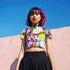 A colorful 90s-style mesh crop top featuring a maximalist abstract pattern. This see-through shirt has a high mock neck, short sleeves, and a vibrant, retro design with geometric shapes, color blocking, and polka dots in bold shades of pink, yellow, blue, and orange. The Y2K-inspired top is a statement piece of festival clothing, perfect for a rave outfit or alternative, dopamine-dressing-inspired streetwear looks.