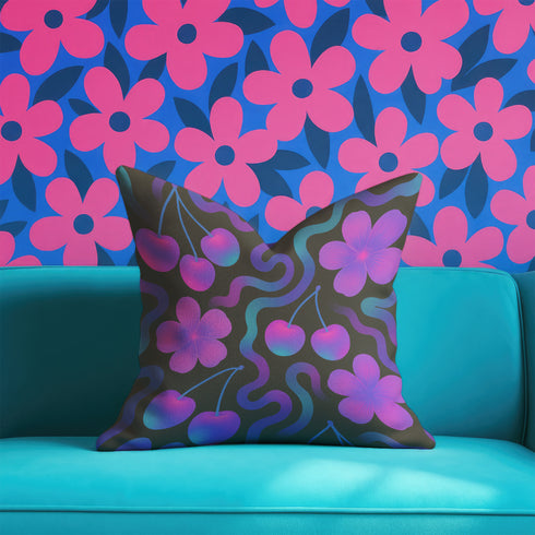 Square throw pillow with a black background featuring a psychedelic pattern of bright pink cherries, purple hibiscus flowers, and wavy teal and magenta lines. Design is bold, colorful, and maximalist.