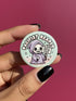 Round pinback button featuring a pastel mint green background with a cartoon grim reaper character in a lavender hood holding a protest sign. The design includes bold black outlined lettering reading “Pacifist Reaper” above the figure and small sparkle accents surrounding it. The finish is glossy and smooth, with a printed illustration style on a metal pin badge surface.