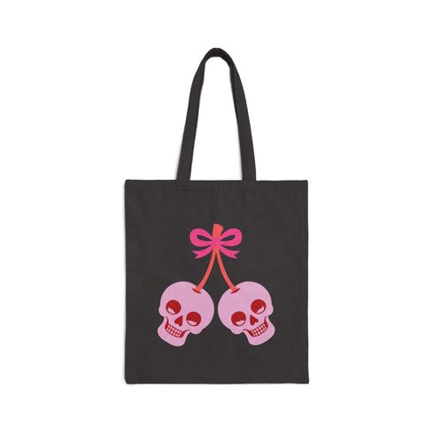 Canvas tote bag featuring pink skull cherries design. Two pink skulls connected by red stem and bow. Quirky gothic-inspired graphic on cream background. Stylish, edgy accessory for everyday use. Perfect for alternative fashion lovers.