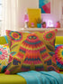 A square faux embroidery pillow featuring a brightly colored maximalist design against a mustard yellow background. In the center stands a stylized, furry Bigfoot or Sasquatch figure rendered in vibrant layers of pink, orange, blue, and lime green with a blue face and yellow eyes. The central creature is surrounded by large, detailed symmetrical pink and blue flowers and leaves. The flat printed fabric creates a highly realistic optical illusion of dimensional crewel embroidery stitches.