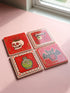 Set of four square glazed ceramic coasters featuring a vibrant pastel goth and creepy cute design. These functional art pieces show a spooky yet playful aesthetic perfect for alternative home decor. The coasters have a glossy wipe-clean finish and a non-slip cork backing to protect furniture surfaces from hot and cold beverages. Ideal for maximalist coffee tables, witchy desks, or as a unique housewarming gift for horror fans who love retro 70s and dopamine decor styles.