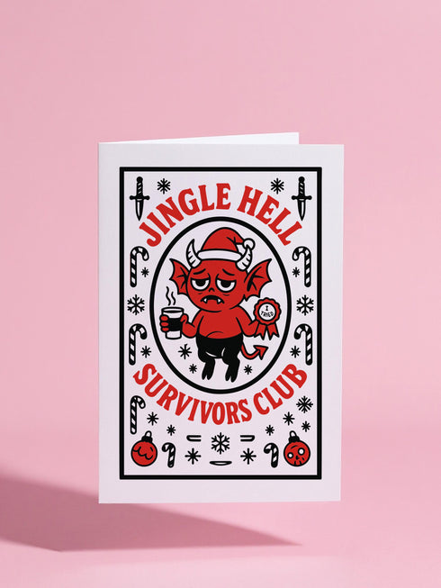 A 5x7 pearlescent shimmer folded greeting card featuring the Jingle Hell Survivors Club design. The front is a illustration of a grumpy red devil imp character, wearing a small Santa hat, holding a coffee cup, and a circular 'I Tried' merit badge. The overall aesthetic is maximalist dark humor and spooky cute. This anti-Christmas card is perfect for those needing relief from holiday stress. Inside text references surviving tolerable relatives, strong eggnog, and merciful hangovers.