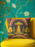 a vibrant yellow chair with a colorful pillow featuring an alien spacecraft and a rainbow, set against a teal floral wallpaper.
