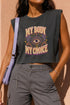 A garment dyed charcoal grey women's muscle tee featuring a slightly cropped boxy fit with structured shoulders and a wide rib collar. The front displays a retro 70s psychedelic graphic printed in purple, orange, and yellow. The text reads MY BODY MY CHOICE surrounding a central eye motif with a radial sunburst, framed by symmetrical mystical swirls and four point stars. The vintage style cotton shirt offers a faded aesthetic, presented on its own without background lifestyle elements.