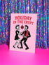 A 5x7 inch greeting card with a vibrant pink background and red retro text reading 'HOLIDAY IN THE CRYPT'. The illustration shows a male and female punk rock skeleton dancing under a red skull disco ball. The female skeleton has a mohawk and wears a black dress. The male skeleton has a mohawk and wears a black jacket with a red vest. Inside, the message reads, 'From our crypt to yours. Eat, drink, and be scary.' The style is a graphic, punk aesthetic.