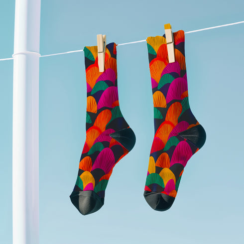Colorful crew socks featuring a bold, fan-shaped mushroom pattern in orange, magenta, teal, yellow, and purple on a deep navy background. The design is vibrant and psychedelic, perfect for statement-making fashion. The socks are mid-calf length with reinforced heel and toe, made from a stretchy polyester, nylon, and spandex blend for comfort and durability.