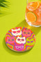 A close-up photograph of a glossy round ceramic coaster featuring a retro 70s psychedelic design. The artwork displays a cluster of six stylized cat face illustrations, each wearing a different pair of sunglasses including retro round and cat-eye shapes. The cats are colored in solid shades of white, hot pink, purple, and lime green. They are set against a vibrant background of wavy, swirling lines in bright orange, red, and purple. The top surface has a highly reflective clear glaze.