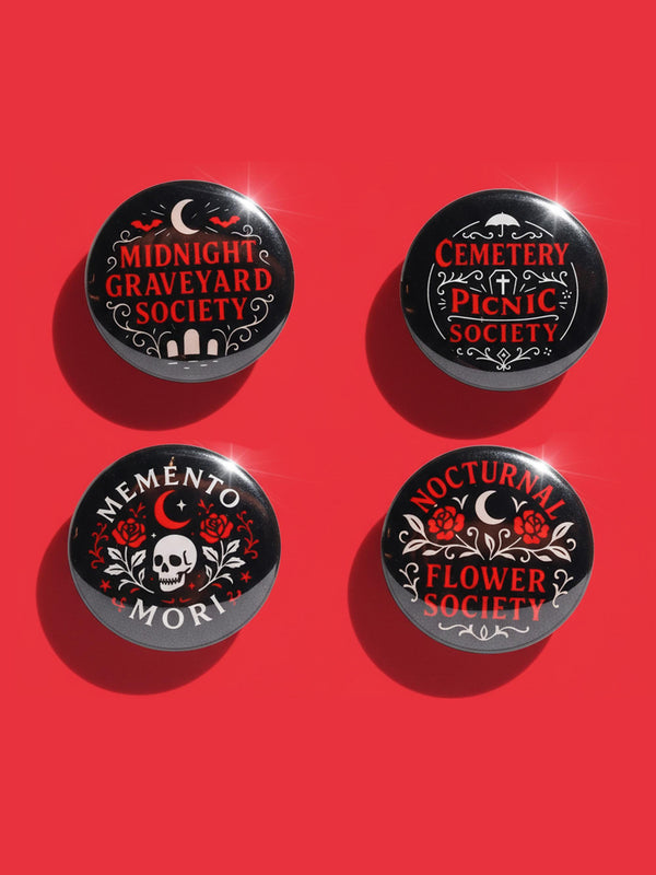A collection of four glossy black circular pinback buttons featuring striking red and white gothic illustrations. One button shows "Midnight Graveyard Society" text with bats and tombstones. Another reads "Cemetery Picnic Society" with a coffin and umbrella icon. A third features a detailed white skull and red roses with "Memento Mori" text below. The final pin displays "Nocturnal Flower Society" surrounded by floral vines.