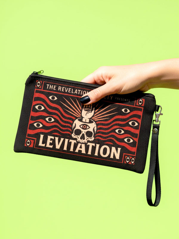 A rectangular makeup bag featuring a vibrant psychedelic print with gothic elements. The fabric texture is clearly visible showing a woven linen-like polyester grain. A black zipper runs across the top edge with a black detachable nylon wrist strap clip on the side, showcasing the approximately nine by six inch dimensions. The print includes high contrast neon colors and trippy swirling patterns typical of maximalist decor.