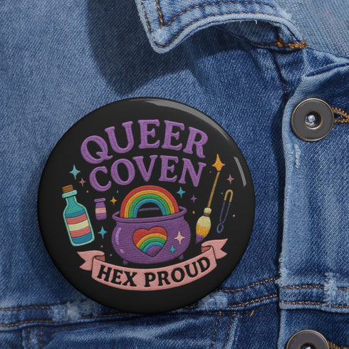 Glossy black pinback button with pastel artwork of a bubbling cauldron, rainbow, potion bottles, and tools. Text reads “Queer Coven, Hex Proud.”