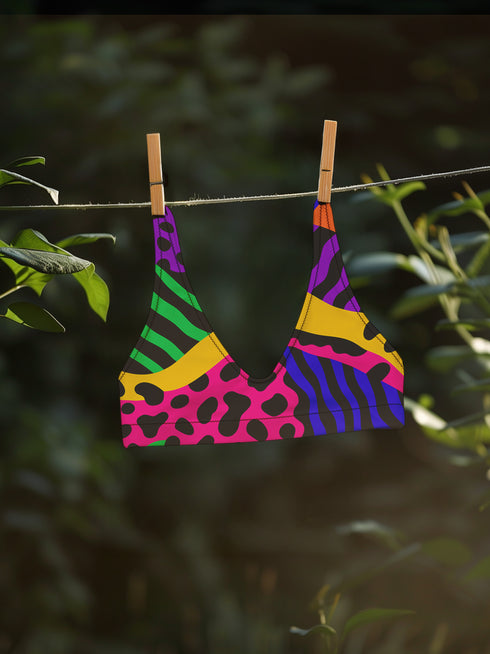 Colorblock animal print bikini top with neon pink, orange, green, purple, and blue abstract pattern. Scoop neck cut with wide straps, removable padding, double-layered fabric, UPF 50+, and made from soft, stretchy recycled polyester-spandex blend.