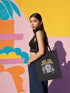 Canvas cotton tote bag with bold “Hex the Patriarchy” design printed on the front, featuring a dripping purple eye in a crystal ball surrounded by pastel potion bottles and hearts. Bag is available in black or natural cotton with long canvas handles.