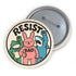 A round white pinback button with the word 'RESIST' in a bold, black, arched font. Below the text stand three cute cartoon characters raising their fists in protest: a green frog with a blue bandana, a pink bunny with '/BAD' on its chest, and a blue shark with sharp teeth. The activist pin has a glossy, protective mylar finish and a durable metal shell, designed as political statement flair for jackets, bags, and backpacks. This punk-inspired, kawaii- badge is a symbol of joyful rebellion.