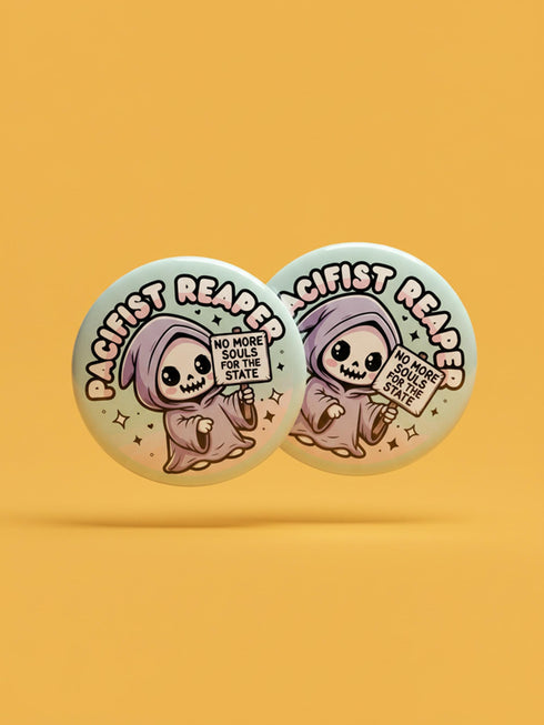 Round pinback button featuring a pastel mint green background with a cartoon grim reaper character in a lavender hood holding a protest sign. The design includes bold black outlined lettering reading “Pacifist Reaper” above the figure and small sparkle accents surrounding it. The finish is glossy and smooth, with a printed illustration style on a metal pin badge surface.