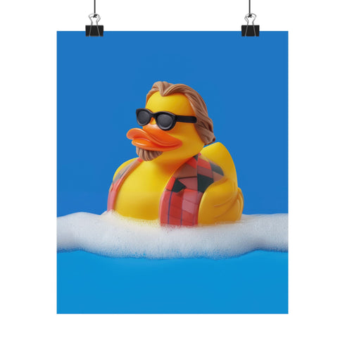 A quirky art print of a rubber duck styled after The Dude from The Big Lebowski, complete with a goatee, sunglasses, and plaid bathrobe. The duck lounges in bubbles, framed in a glossy red frame, with a manicured hand adjusting it against a monochromatic red backdrop.