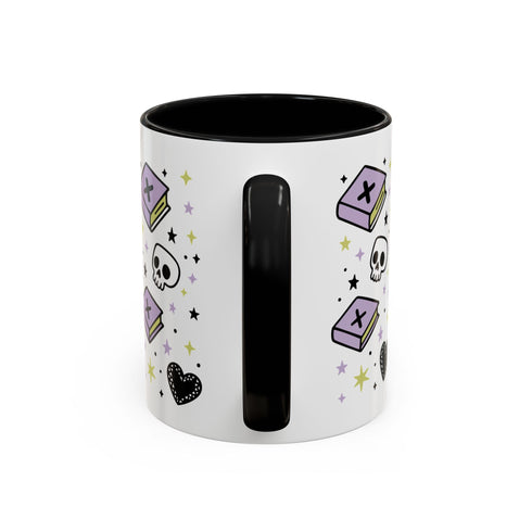 The Gothic Read Dangerously Mug Accent Coffee Mug (11, 15oz) features a black handle and interior, purple spell book and skull illustrations, black hearts, colorful stars, is BPA-free, and has a glossy finish for safe and stylish sipping.