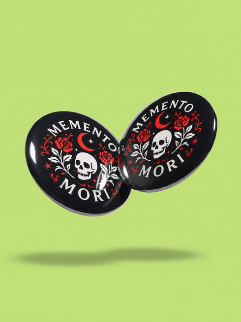 A collection of four glossy black circular pinback buttons featuring striking red and white gothic illustrations. One button shows "Midnight Graveyard Society" text with bats and tombstones. Another reads "Cemetery Picnic Society" with a coffin and umbrella icon. A third features a detailed white skull and red roses with "Memento Mori" text below. The final pin displays "Nocturnal Flower Society" surrounded by floral vines.