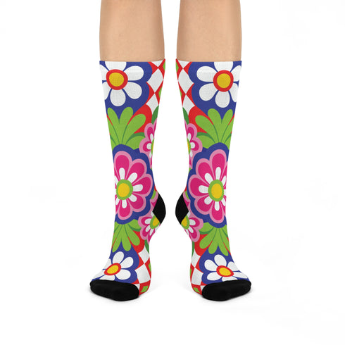 Mid-calf crew sock with a bold 70s psychedelic floral print. The design mixes a red and white diagonal checkerboard with oversized retro flowers, including white daisies with bright yellow centers and a large hot pink bloom with a white inner layer, set over a royal blue background with green leafy foliage. The toe and heel are solid black. The fabric is a soft, stretchy printed knit, made as a one-size unisex statement sock for maximalist and dopamine dressing looks.