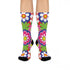 Mid-calf crew sock with a bold 70s psychedelic floral print. The design mixes a red and white diagonal checkerboard with oversized retro flowers, including white daisies with bright yellow centers and a large hot pink bloom with a white inner layer, set over a royal blue background with green leafy foliage. The toe and heel are solid black. The fabric is a soft, stretchy printed knit, made as a one-size unisex statement sock for maximalist and dopamine dressing looks.