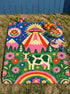 A rectangular velveteen minky blanket with a bright, maximalist design. The top half features a vibrant blue sky with a pink, green, and yellow UFO beaming rays down over hot pink snow-capped mountains. The bottom half shows a grassy green field with a white cow covered in dark spots, surrounded by large, colorful red, pink, and blue retro flowers, pine trees, and a rainbow arch at the very bottom. The reverse side is a fluffy off-white sherpa.