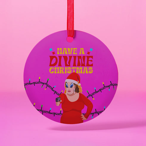 Round purple metal Christmas ornament featuring Drag Queen Divine in Santa hat and red dress with colored Christmas lights. Text reads "Have A Divine Christmas" in retro psychedelic lettering.