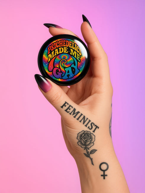 Round glossy pinback button measuring 2.25 inches featuring a vibrant rainbow psychedelic swirl with retro-style text that reads “Psychedelics Made Me Gay.” The background is a mix of rainbow waves and sparkles, with bold, colorful typography in orange, yellow, and blue. Made from durable tinplate with a safety pin backing, scratch-resistant mylar coating, and a high-gloss finish. Ideal for jackets, backpacks, or pride festival accessories.