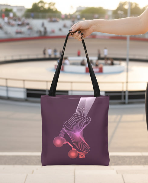 A person is holding a purple tote bag with a graphic of a rollerblader on it, in front of a blurred background of a skate park or racetrack.