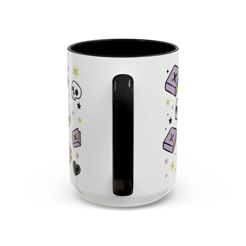 The Gothic Read Dangerously Mug Accent Coffee Mug (11, 15oz) is a white ceramic mug with a black handle and interior, decorated with purple tombstones, skulls, stars, and hearts. BPA-free and shown from the back with the handle centered.
