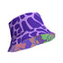 Reversible unisex bucket hat featuring two distinct designs - one side showcases a vibrant floral pop art pattern with purple, pink, green and blue splashes and organic flower motifs, while the reverse side displays a purple giraffe print pattern with dark purple giraffe spots on a light purple background. Made from 100% polyester with textured linen feel, this moisture-wicking and breathable hat is available in XS, S/M, and L/XL sizes for ultimate style versatility.