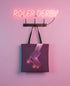 A neon sign reading "ROLLER-DERBY" is hanging on a wall, with a tote bag featuring a graphic of roller skates below it.