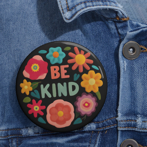 Bold "BE KIND" pinback button featuring vibrant psychedelic flowers in hot pink, teal, yellow, and orange on black background. Retro 70s-inspired typography in coral and mint green surrounded by colorful blooms. Statement activist accessory perfect for punk fashion, protest wear, and battle vests. Glossy UV-resistant finish with safety pin backing available in 2" and 3" sizes.