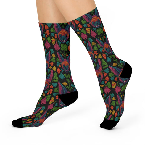 Colorful mid-calf socks with a black background featuring a whimsical folk-art bat pattern in rainbow tones of pink, orange, teal, and green, paired with matching heels and toes.