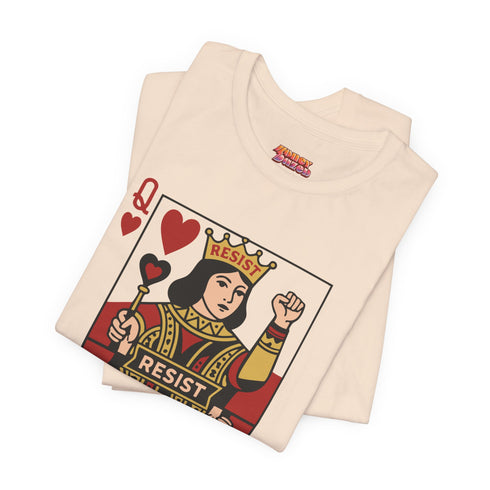 A centralized graphic design of a Queen of Hearts playing card on a cream or pink unisex t-shirt. The Queen is depicted in a maximalist folk art style, holding a heart-topped scepter and a raised fist in a gesture of solidarity. The word "RESIST" is visible on her crown and a central banner in ochre and true red tones. The layout is a centralized medallion style with rust and ochre accents and a playing card border.