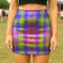 A woman wearing a colorful, patterned mini skirt stands in a grassy field.