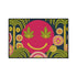 A rectangular doormat featuring a large hot pink smiley face on a deep teal background. The smiley face has green cannabis leaves for eyes and a yellow stitched-style smile. The central face is surrounded by stylized green foliage arches and concentric circles in pink, yellow, and white, resembling abstract flowers. The design mimics a vintage needlepoint or tapestry texture but is a flat print. The mat has a solid black trim border.