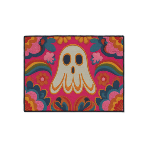 A rectangular polyester doormat with a vibrant, psychedelic design on a hot pink background. In the center is a cute, cartoonish ghost in off-white with yellow and orange outlines; it has large, dark, expressive eyes. The ghost is surrounded by a maximalist pattern of 70s-style floral motifs and puffy clouds in shades of teal, blue, orange, and light pink. Two small, colorful rainbows arc over the ghost's shoulders. The doormat has a durable, textured surface and is framed by a sleek black trim.